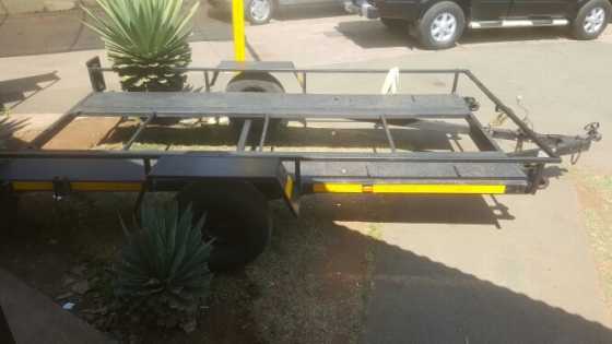 Tilting trailer with secure strapping