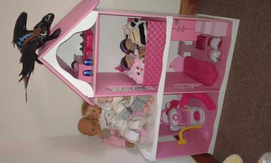 Wooden barbie doll house with a bed, cupboard, bath, lounge suite and basin.